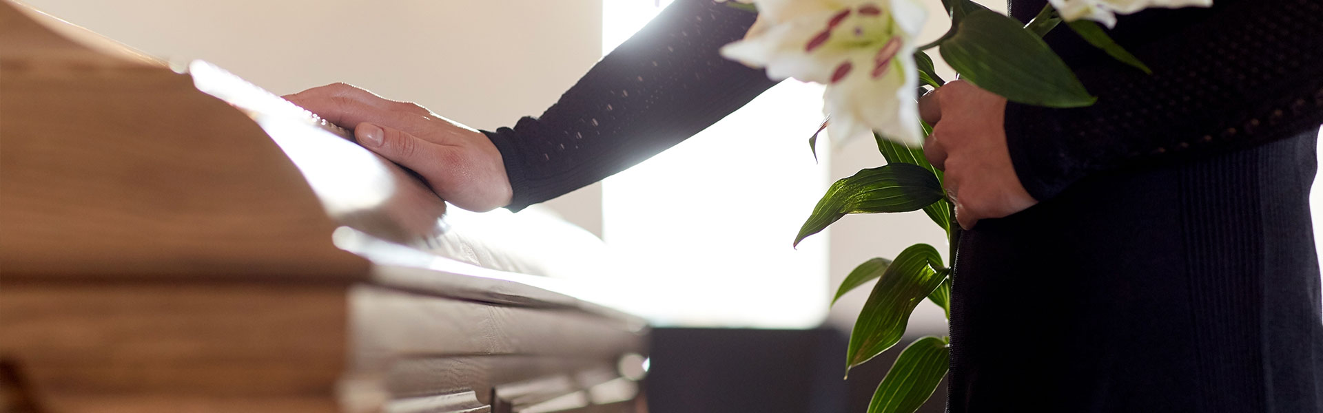 man touching a coffin holding a flower