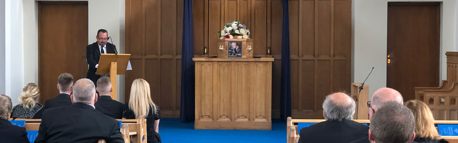 funeral service in a blue carpeted room small image